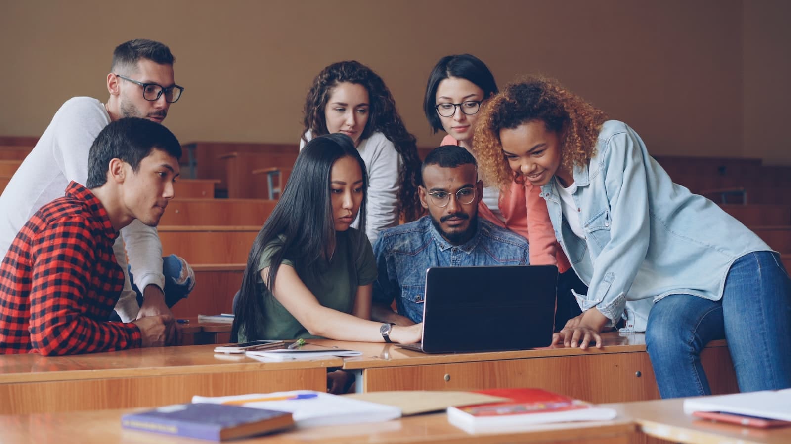 A group of students collaborating around a laptop